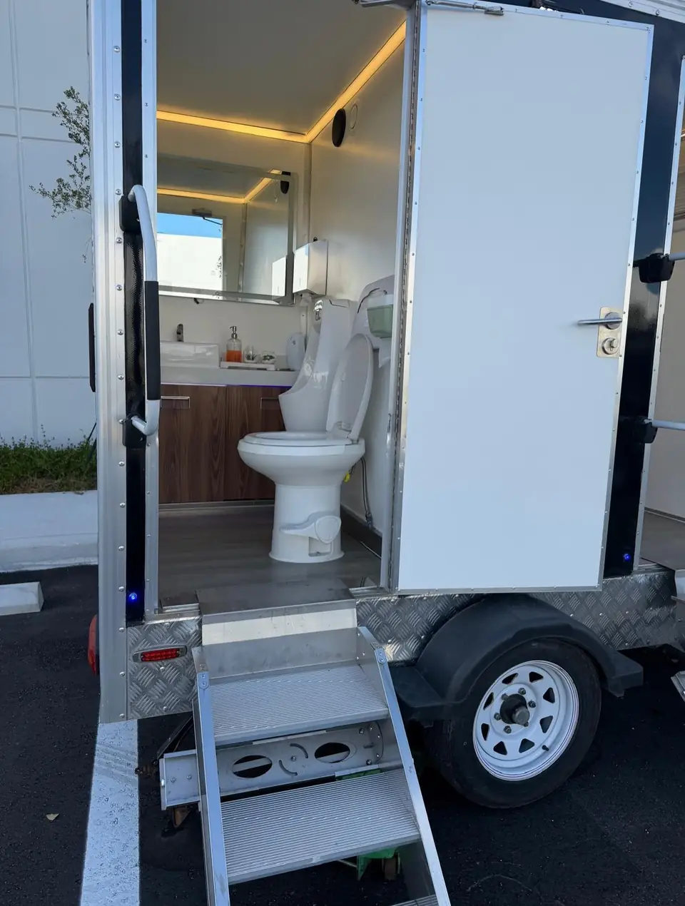 Restroom trailer stall with porcelain toilet and wood vanity