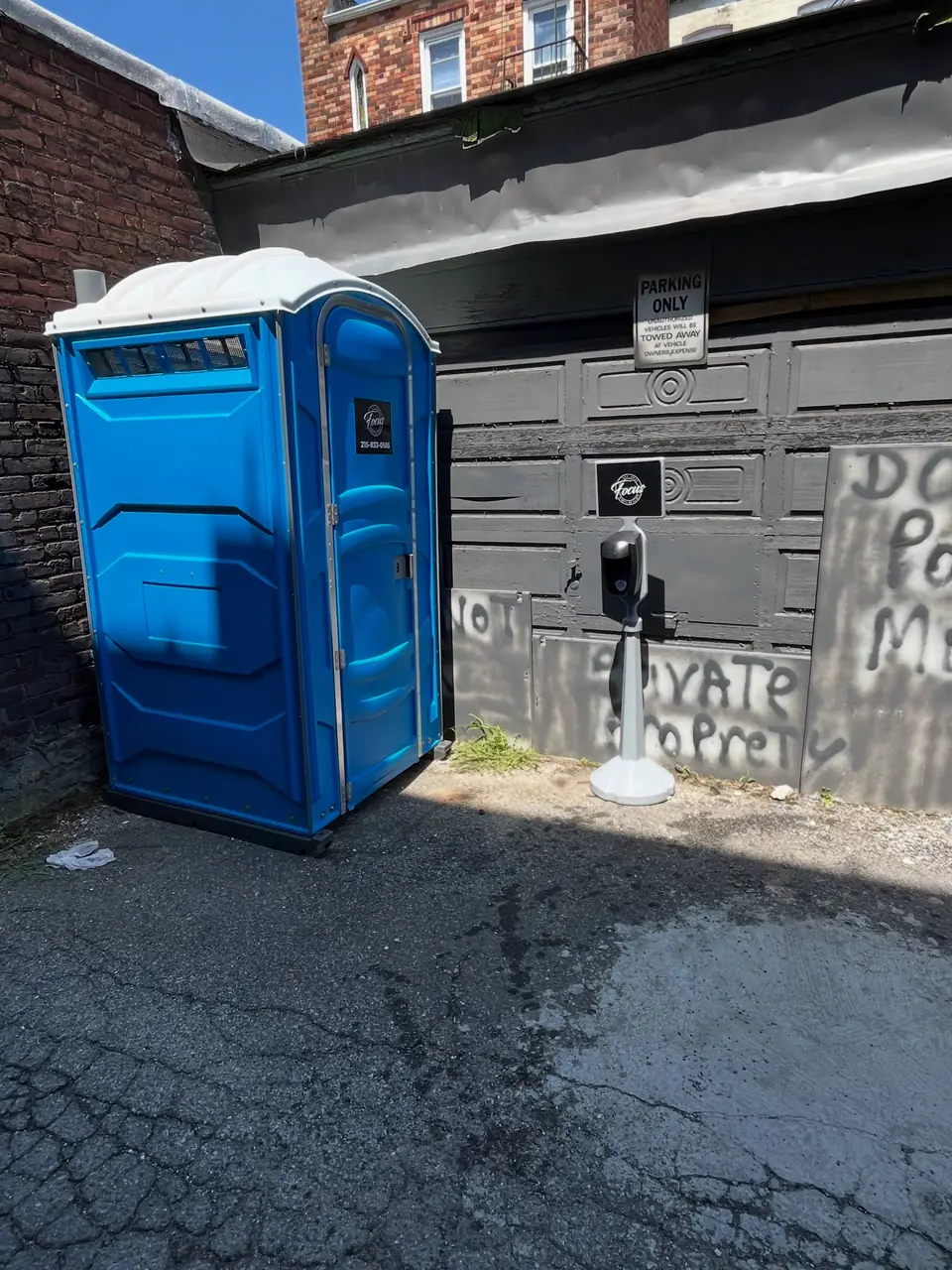 Porta potty placed on pavement beside a garage, a typical Mexico driveway setup