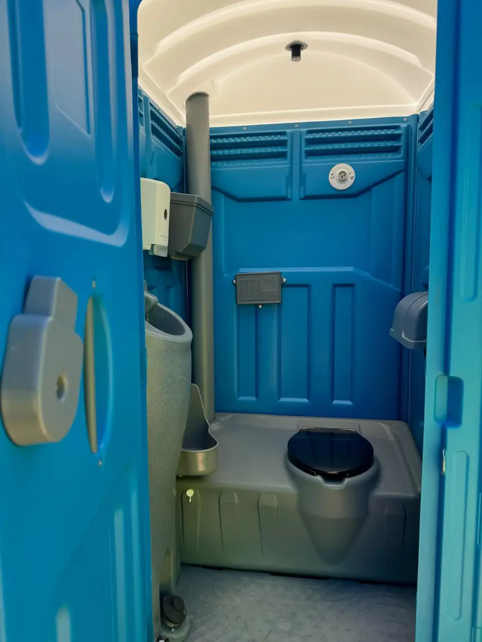 Inside a standard porta potty showing the seat and urinal