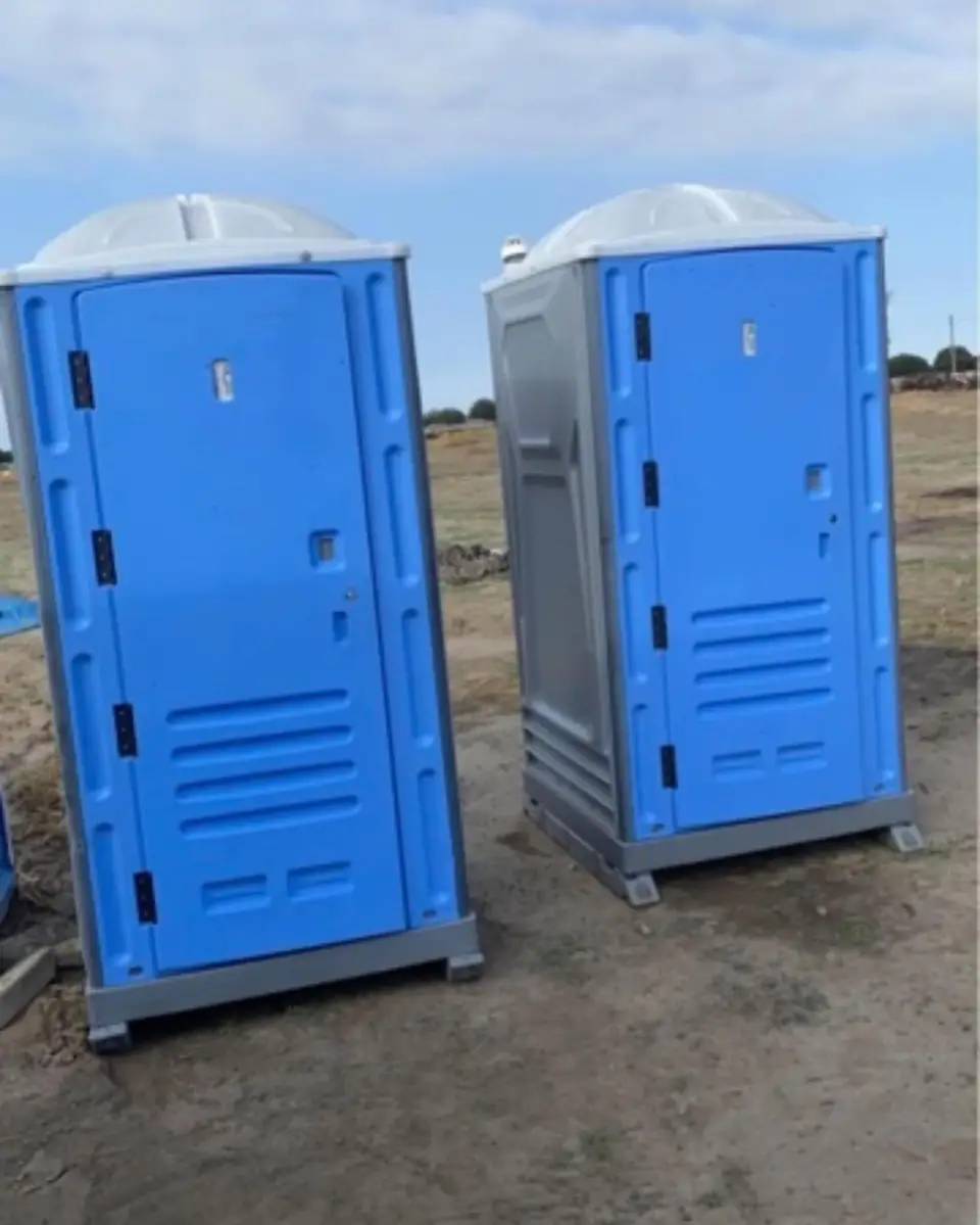 Two standard porta potties on a graded lot, the setup most Belle job sites use